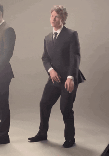 a man in a suit and tie is dancing in front of another man