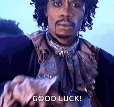 Prince-like performer points forward with “GOOD LUCK!” text.