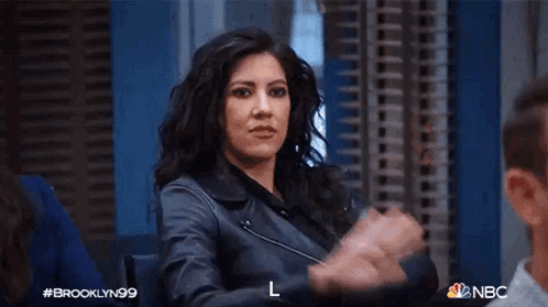 Amy Santiago raises a hand for a high five in an office.