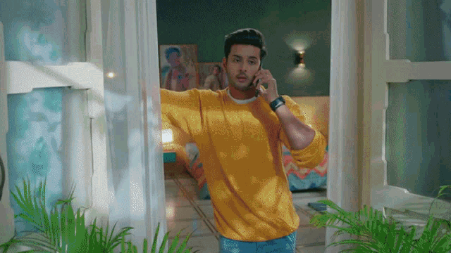 a man in a yellow sweater is talking on his cell phone