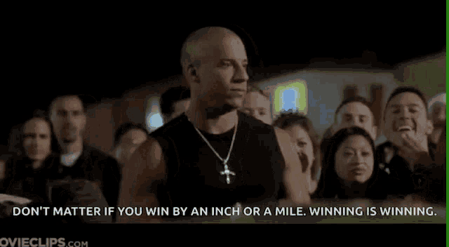 a man in a black tank top is standing in front of a crowd .