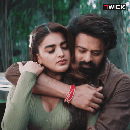 a man and a woman are hugging with a wick logo in the background