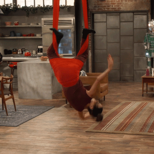 a woman in a red outfit is upside down in a kitchen