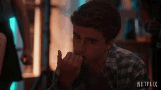 a man in a plaid shirt is biting his nails in a netflix ad