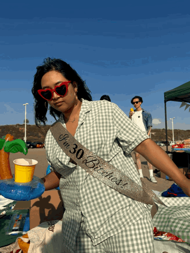 a woman wearing sunglasses and a sash that says i 'm 30 years