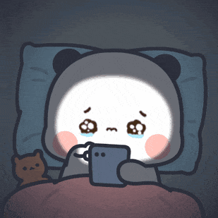 A panda-like cartoon character lies in bed crying while looking at a phone.