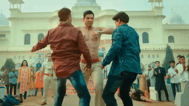a shirtless man is being punched by two other men