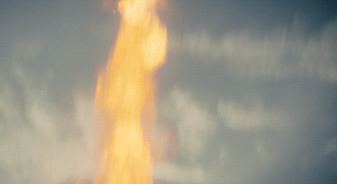 a tall flame against a cloudy sky