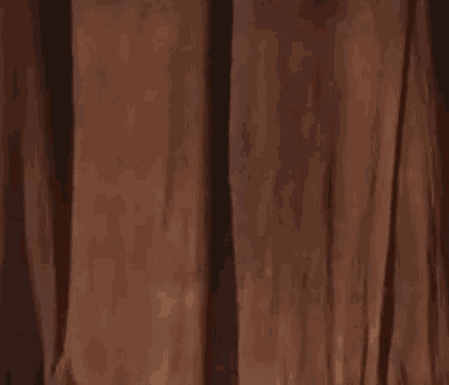 a man is peeking out from behind a curtain and making a surprised face .