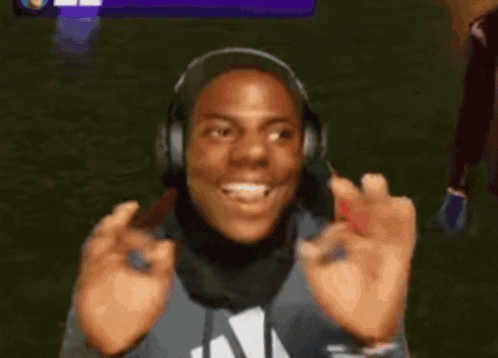 a man wearing headphones and a scarf is smiling and making an okay sign with his hands .