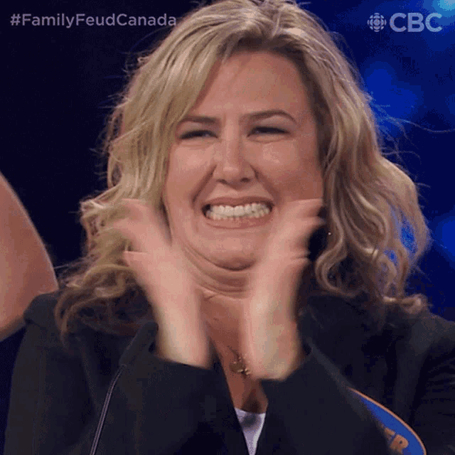 a woman applauds in front of a sign that says cbc on it