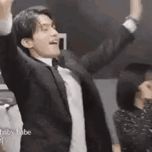 a man in a suit and bow tie is dancing with his arms in the air .