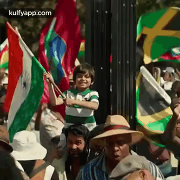a boy is holding a flag in front of a crowd of people .