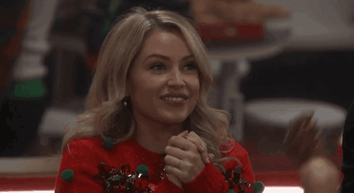 a woman is wearing a red sweater with green pom poms