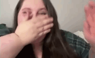 A woman covers her mouth in a startled reaction.