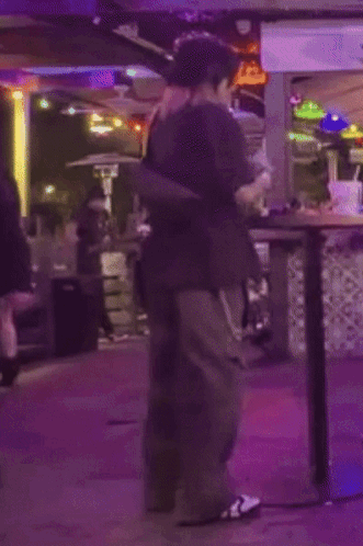 a man in a black shirt is standing in front of a table with a purple light behind him