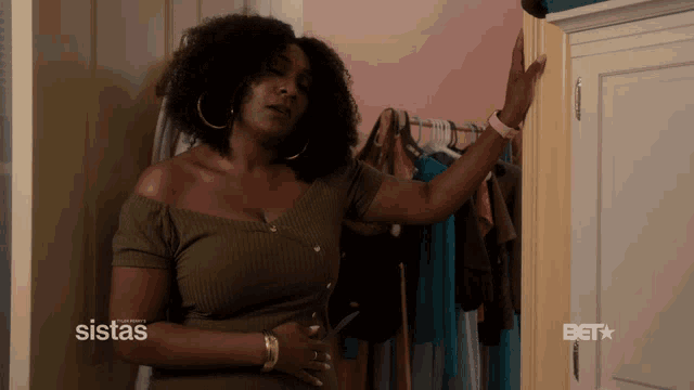 a woman standing in front of a closet with a bet logo on the bottom right