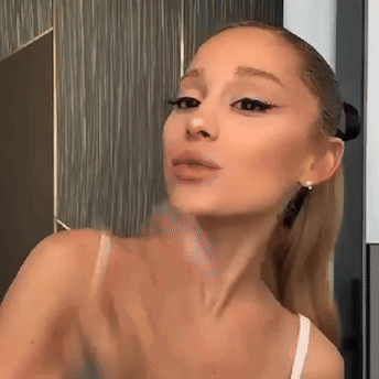 ariana grande is taking a selfie in front of a mirror .