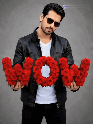 A man in sunglasses holds a bouquet shaped from red roses.