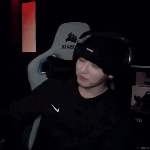A streamer in headphones reclines in a gaming chair.