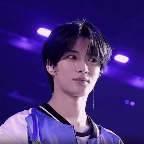 a close up of a person 's face with purple lights behind him