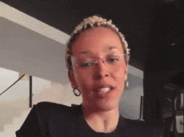 a close up of a woman 's face with glasses and a black shirt