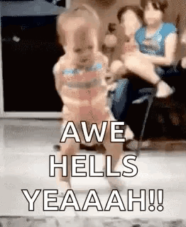 a woman is holding a baby in her arms and a baby is walking on a floor .