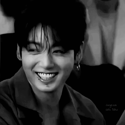 A black-and-white close-up captures a broad, joyful smile.