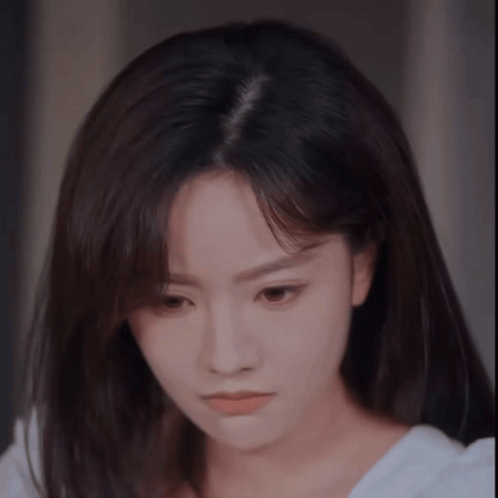 A woman looks downward with a quiet, sulking expression.