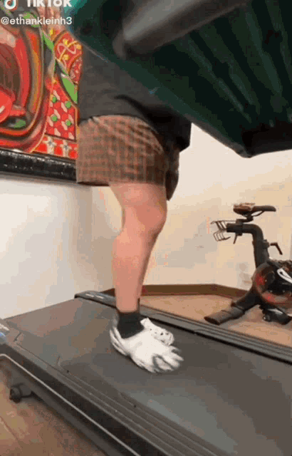 a person is walking on a treadmill with a bicycle in the background .