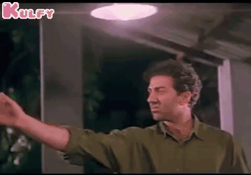 a man in a green shirt is standing in front of a light with his arm outstretched .