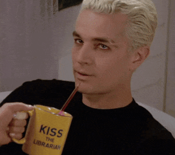 a man drinking through a straw from a yellow cup that says kiss the librarian