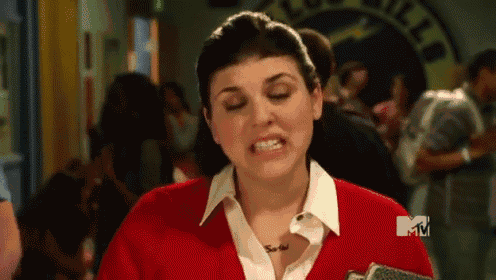 A woman in a red uniform gives an awkward expression in a busy interior.