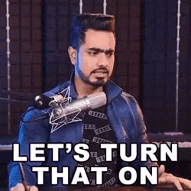 a man is sitting in front of a microphone with the words `` let 's turn that on '' .