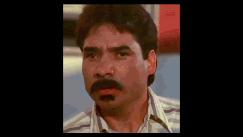 a man with a mustache is making a funny face while wearing a striped shirt .