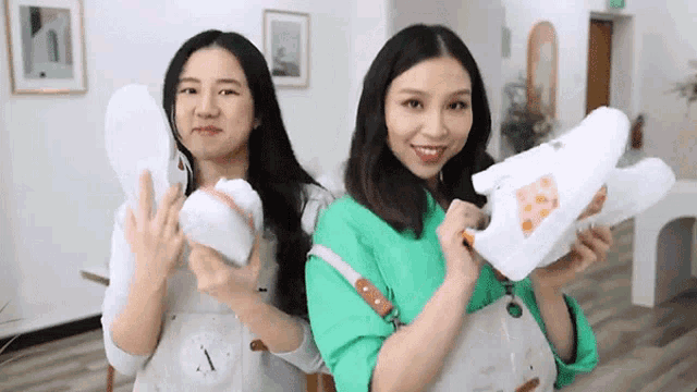 two women are standing next to each other holding shoes and a purse .