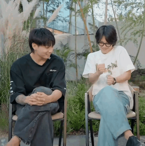 a man wearing a t-shirt that says tears sits next to another man in a chair