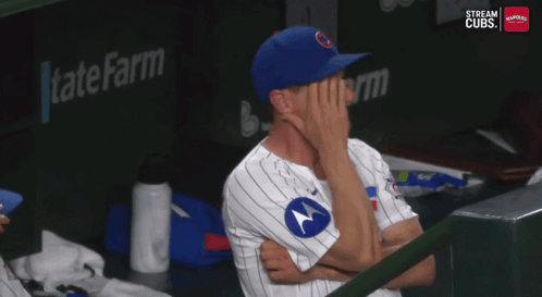 a man in a cubs uniform covering his face with his hands