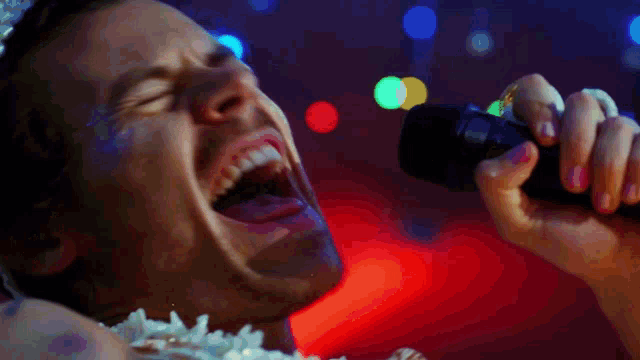 a close up of a man singing into a microphone
