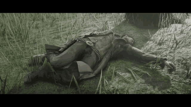 a man is laying in the grass with a gun