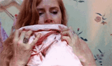 A woman clutches a blanket to her face in a crying, overwhelmed reaction.