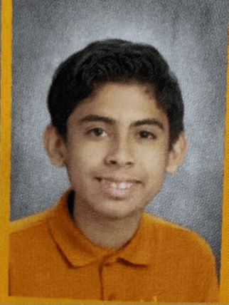 a young boy wearing an orange shirt is smiling for a picture