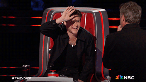 a man giving a high five while sitting in a chair with a nbc logo in the corner