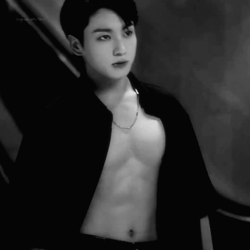 A black-and-white fashion image shows an open black shirt and necklace.