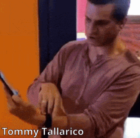 a man in a pink shirt is using a tablet with the name tommy tallarico on the bottom