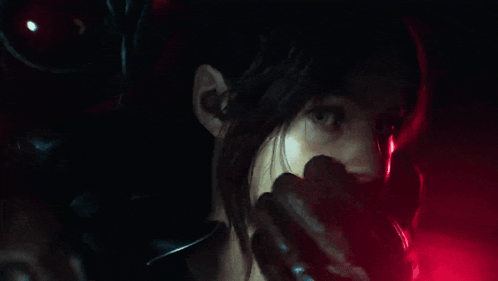 a close up of a woman 's face in a dark room with a red light behind her