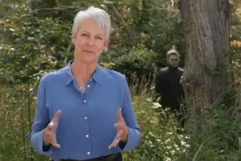 an older woman in a blue shirt is standing in a forest
