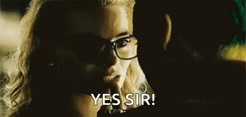 a woman wearing glasses is talking to a man in a movie .