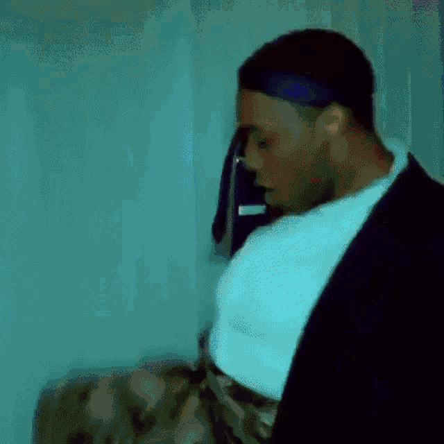 a man in a suit and white shirt is standing in a room with a towel hanging on the wall .
