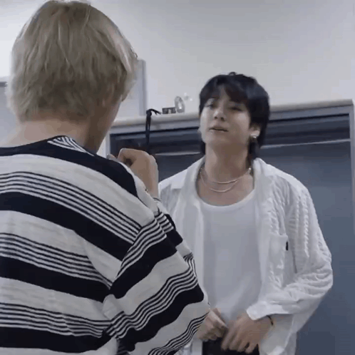 two men are standing next to each other in a room and one of them is wearing a striped shirt .